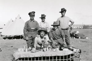 Weary Australian soldiers with the Christmas lunch laid out on a makeshift table in 1915.