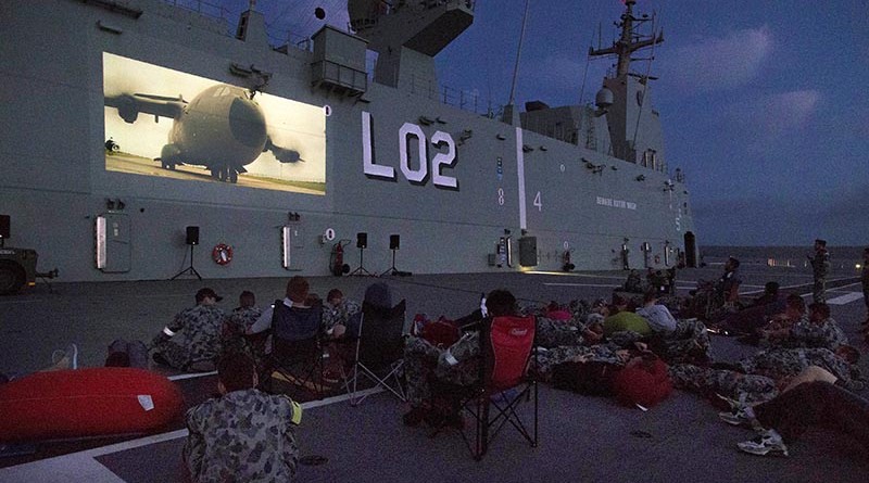Crew members watch a movie on the side of HMAS Canberra.
