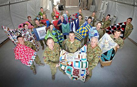 Soldiers pose with handmade quilts